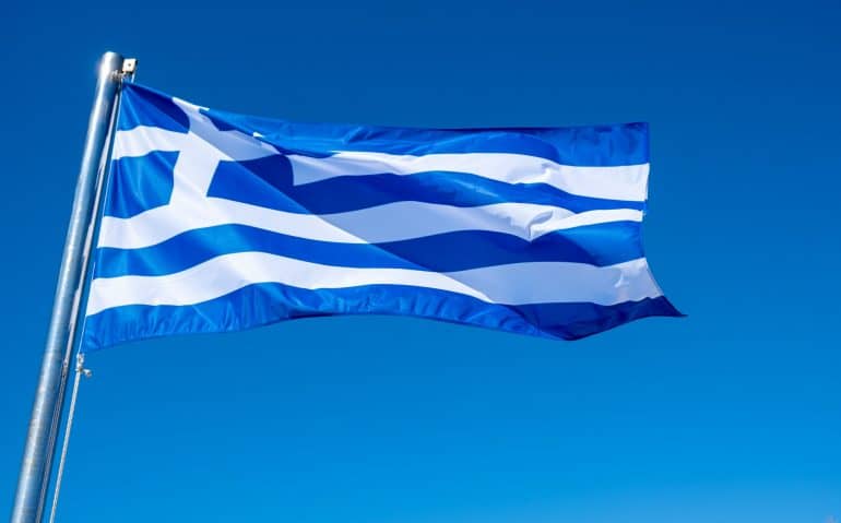 Greek flag waving against blue sky background.